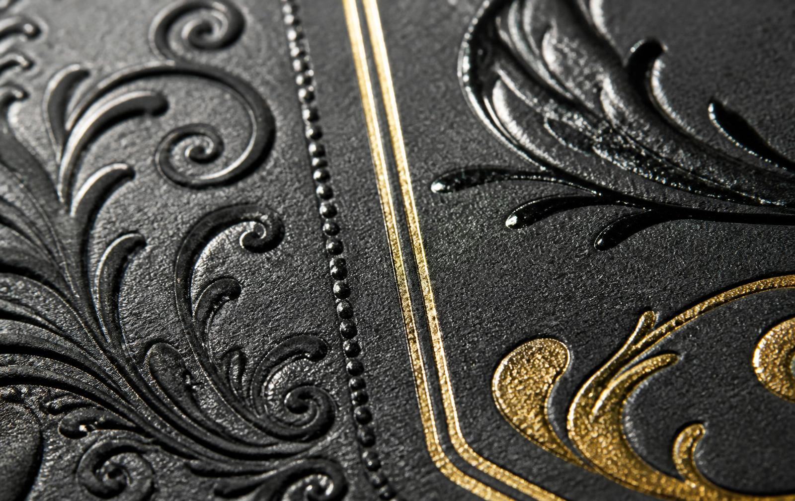 Detalhe macro de papel com laminação, verniz, hot stamp e relevo.
